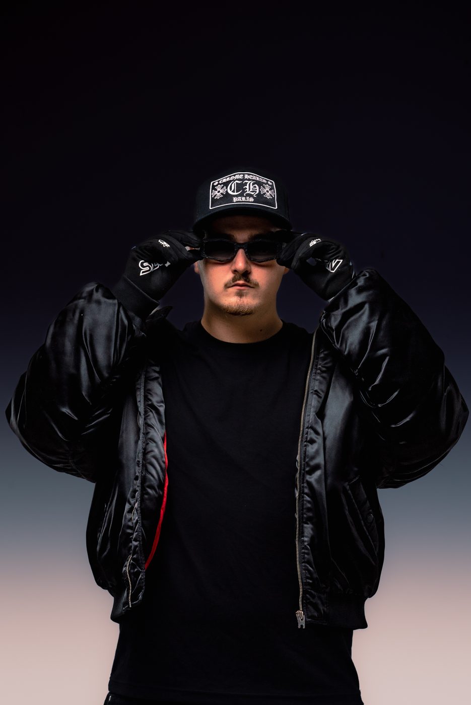 ALVA DJ holding the brim of his cap, wearing a black puffer jacket