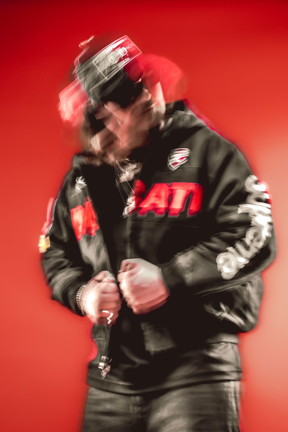 Motion-blurred portrait of ALVA DJ in a leather racing jacket on a red background